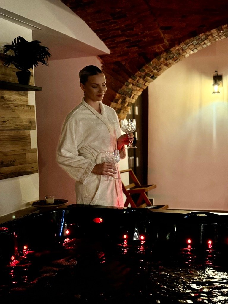 Tower Spa Celje – gostja v kopalnem plašču s kozarci ob jacuzziju